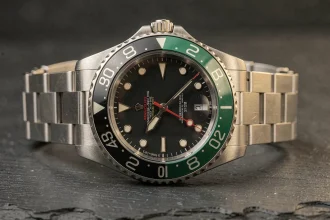 Rolex GMT-Master II 126710GRNR avec lunette céramique noire et verte posée sur une surface en ardoise sombre, vue macro détaillée du cadran et du bracelet Oystersteel